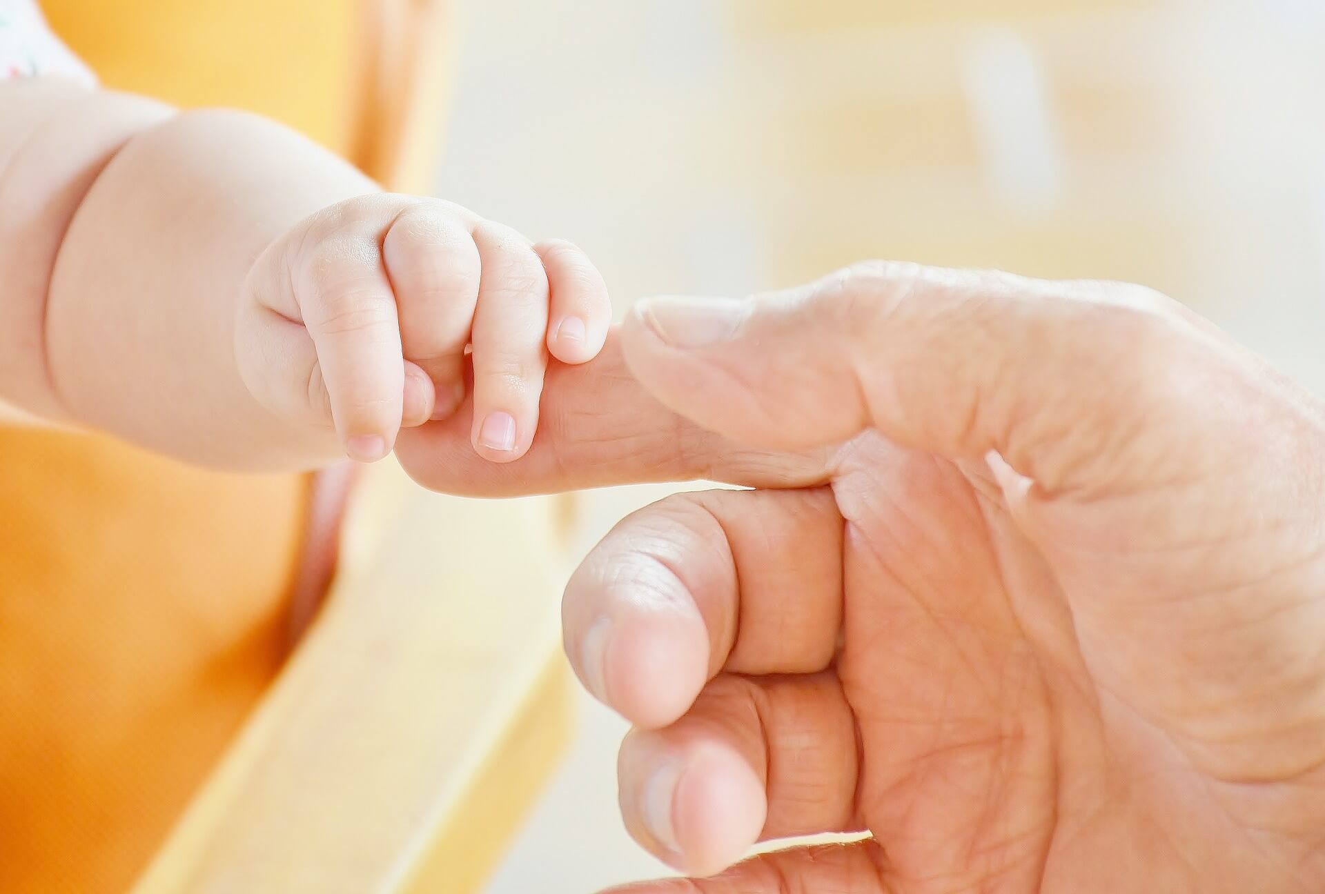 Une maman tient le doigt de son jeune nourrisson